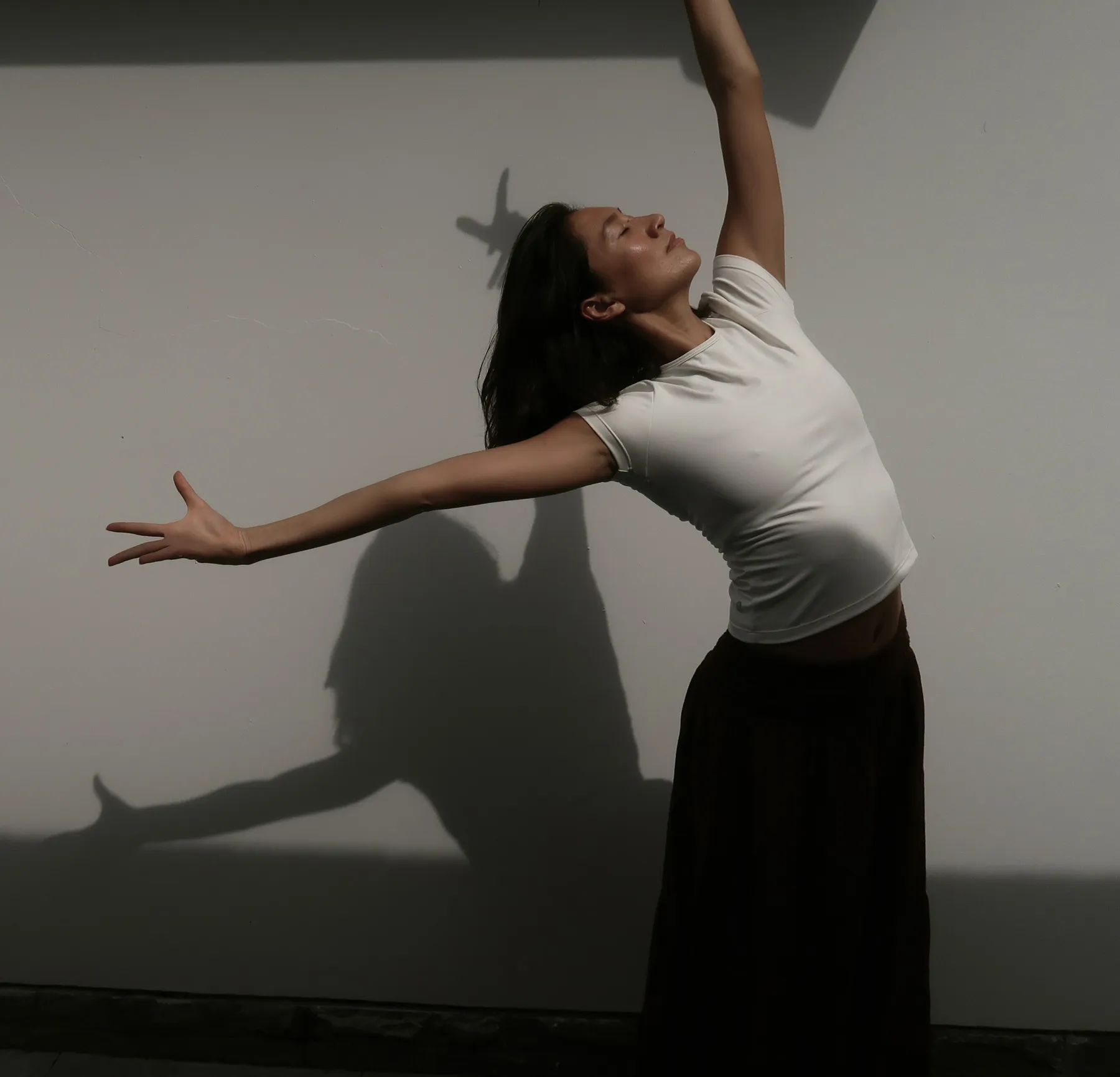 Dancer crouching on the studio floor beside a mirror